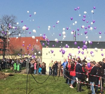 Das Bild zeigt Gäste beim Richtfest, die farbige Luftballons steigen lassen