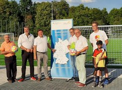 Quelle: Stadt Werne Auf dem Bild sind sieben Erwachsene und ein Kind zu sehen. Im Hintergrund befindet sich ein Fußballtor und ein Plakat.