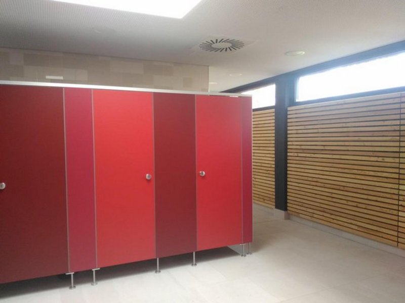 Das Bild zeigt rote Umkleidekabinen, am Bildrand ist eine holzverkleidete Wand zu sehen.