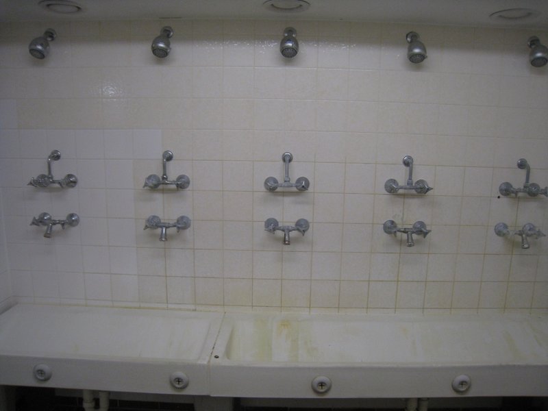 Man sieht eine Gemeinschaftsdusche mit fünf Duschköpfen.