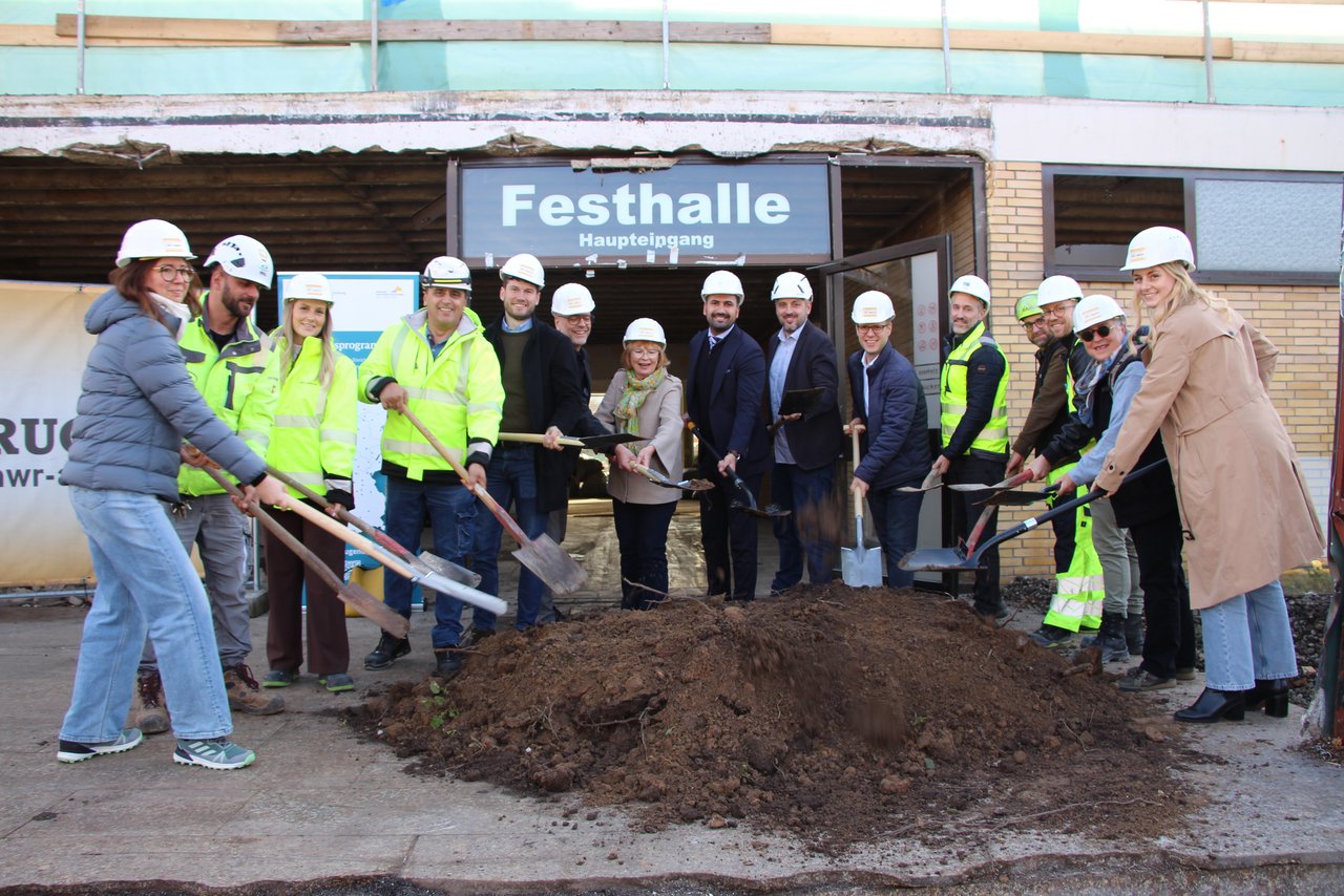 Quelle: Gemeinde Sandhausen Das Bild zeigt einen Spatenstich. Eine Gruppe mit Baustellenhelml und Spaten sticht in einen Sandhaufen.