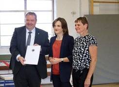 Quelle: Elisabeth Kaiser Man sieht drei Personen mit einer Urkunde.