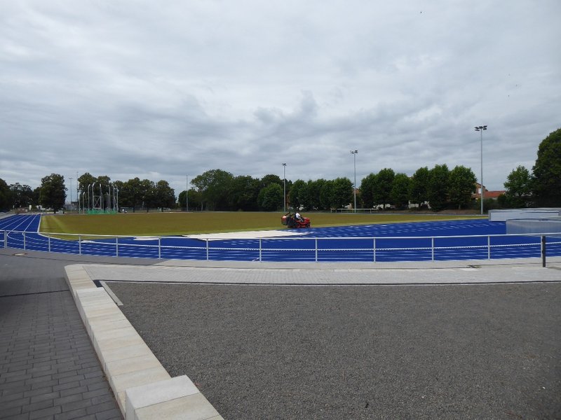 Das Bild zeigt eine Sportaußenanlage mit Rasenfläche in der Mitte.