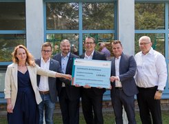 Quelle: Eventfotoservice Frenzel/ Ruhleben Man sieht sechs Personen, die einen symbolischen Spendenscheck an die Stadt Ruhland lachend in die Kamera halten.
