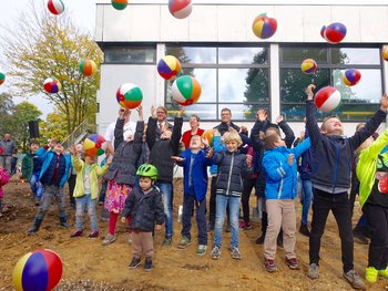 Das Bild zeigt Kinder und Erwachsene beim Spatenstich