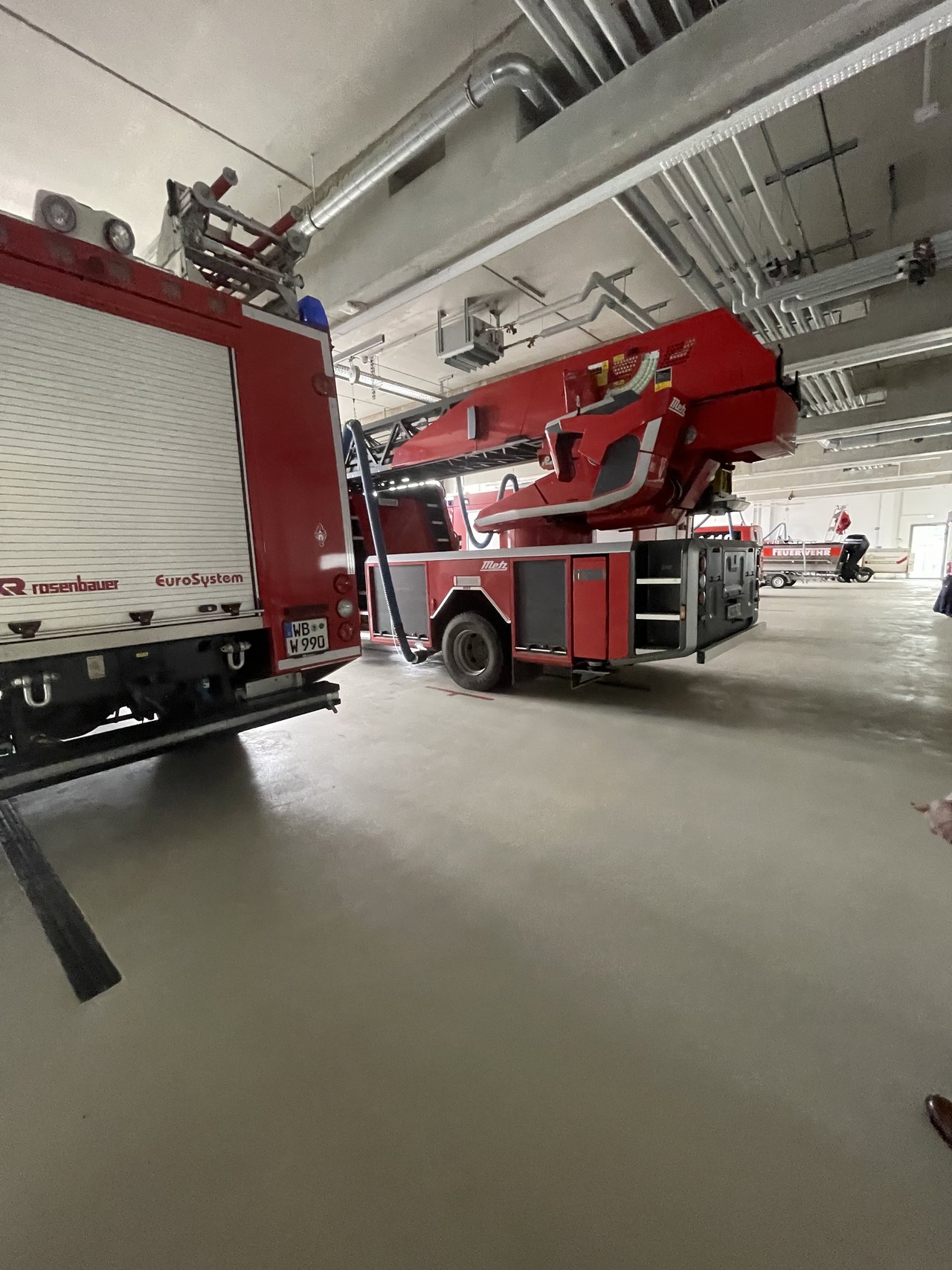 Man sieht zwei Feuerwehrautos von hinten und ein Feuerwehrboot.