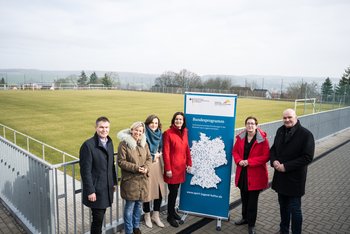 Copyright: Stefanie Loos Man sieht sechs Personen, die an einem Fußballplatz neben einem Roll-Up stehen.