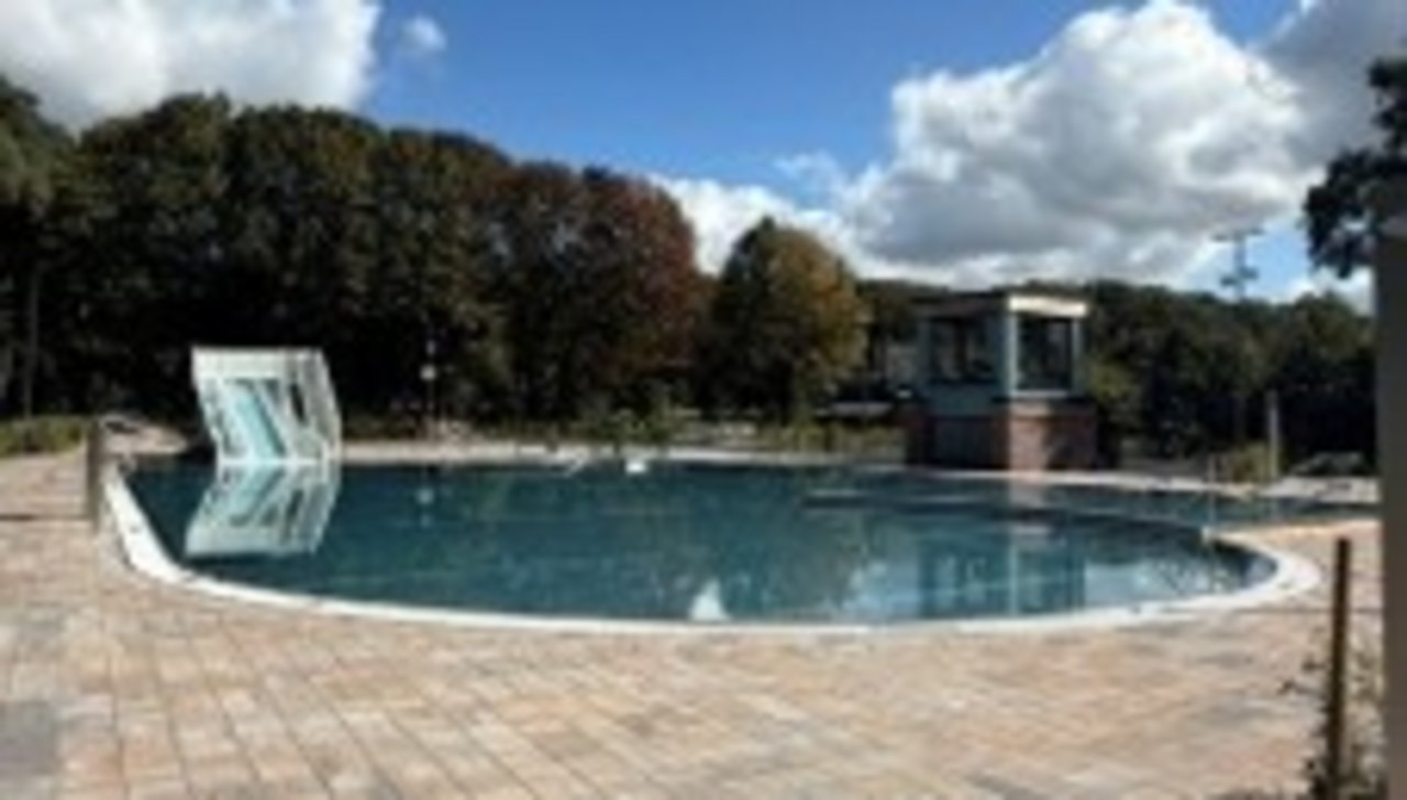 Das Bild zeigt ein saniertes Freibad. Man erkennt ein Schwimmbecken und eine Wasserrutsche.