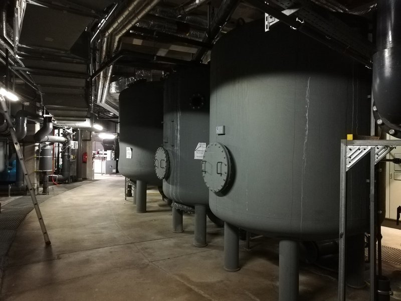 Man sieht einen Boiler in einem großen Technikraum.