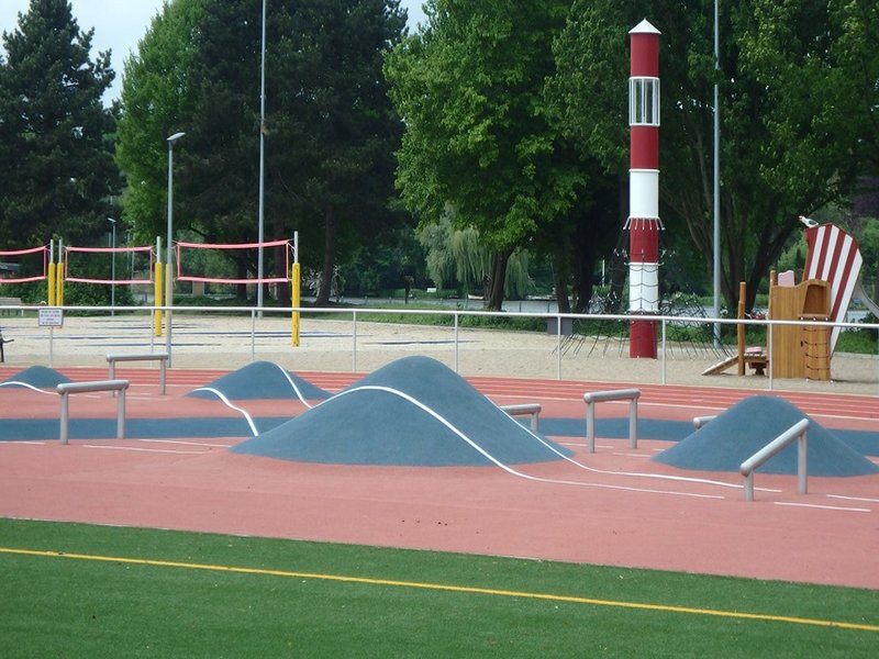Das Bild zeigt eine Sportanlage mit Hindernis-Parcour, im Hintergrund ist ein Beachvolleyballfeld zu sehen.