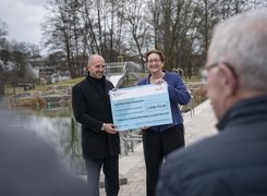 Quelle: bundesfoto - Rumpenhorst Mna sieht eine Frau und einen Mann, die lachend einen übergroßen Scheck in die Kamera halten und in einem Freibad stehen.