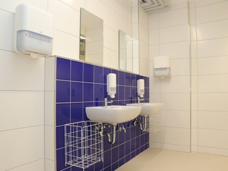 Das Bild zeigt zwei Waschbecken an einer blau gefliesten Wand.