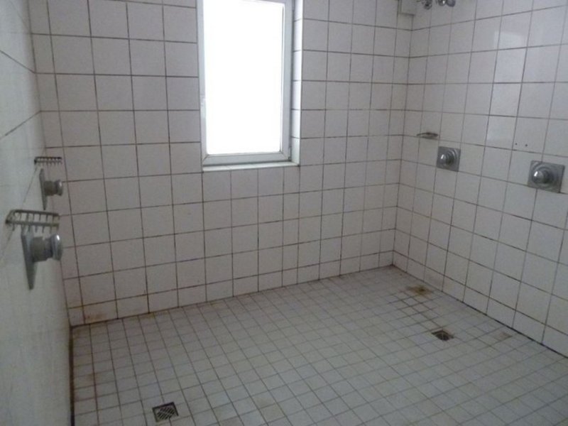 Das Bild zeigt eine weiß geflieste Sanitärfläche mit mehreren Duschen.