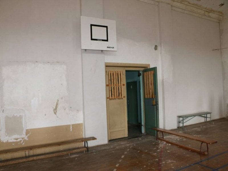 Das Bild zeigt eine Turnhalle von innen, es ist ein Basketballkorb an der Wand zu sehen.