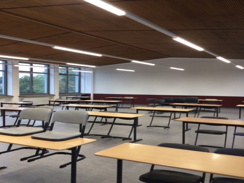 Das Bild zeigt einen Klassenraum mit Tischen und Stühlen.