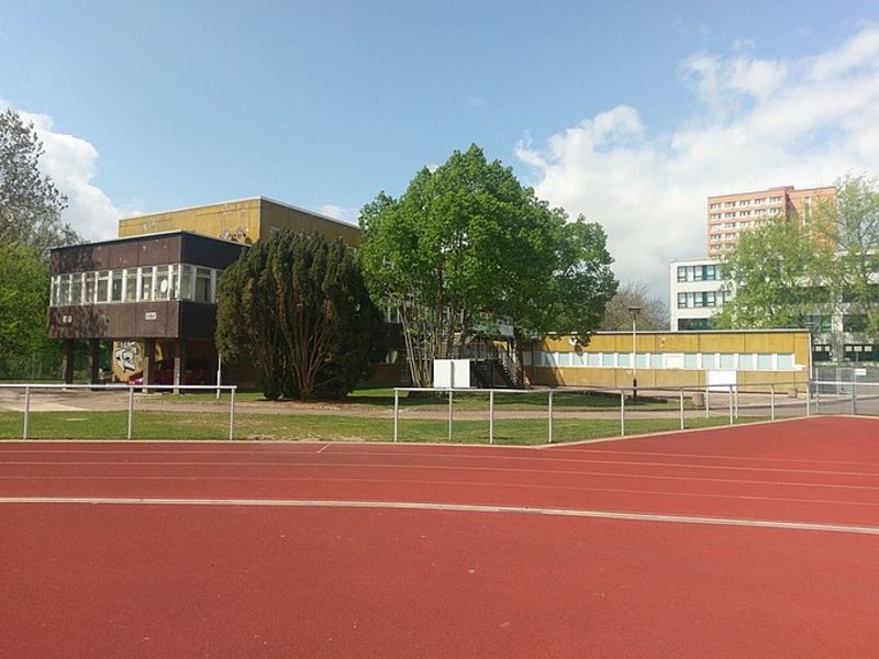 Das Bild zeigt einen Sportplatz, im Hintergrund ist ein Gebäude zu sehen.