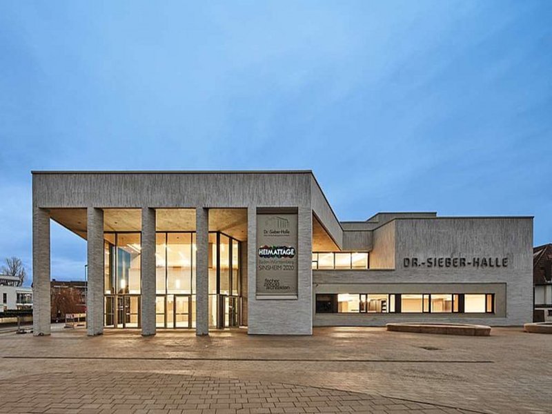 Das Bild zeigt ein modernes Gebäude in der Abenddämmerung, das den Schriftzug Dr.-Sieber-Halle trägt.