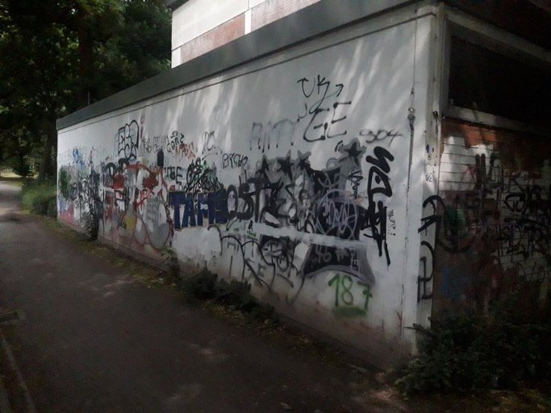 Das Bild zeigt die Fassade eines Gebäudes, darauf sind mehrere Graffitis zu sehen.