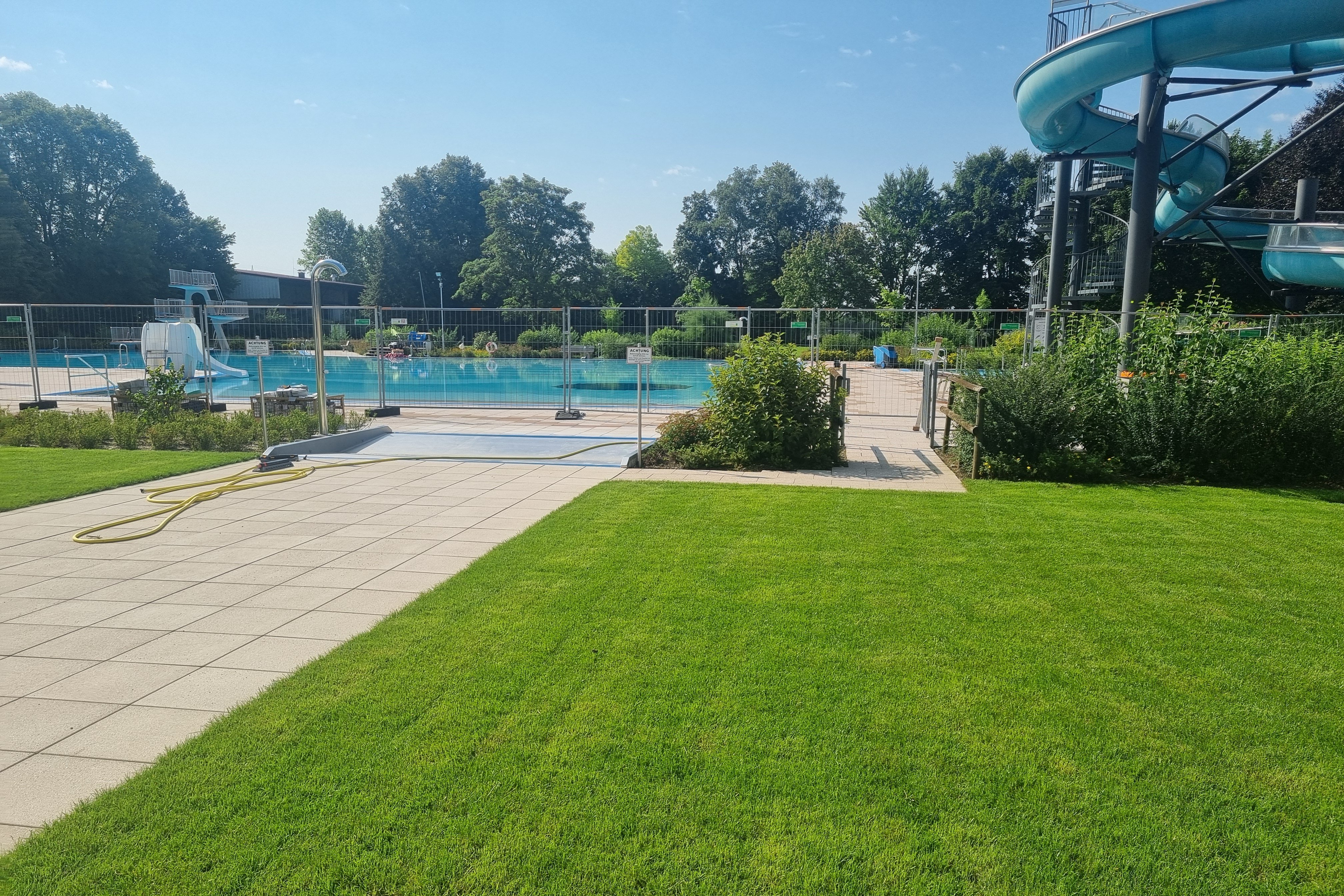 Gemeinde Kirchdorf/Iller Das Bild zeigt ein Freibad mit Schwimmbecken, Wasserrutsche und grünem Rasen.