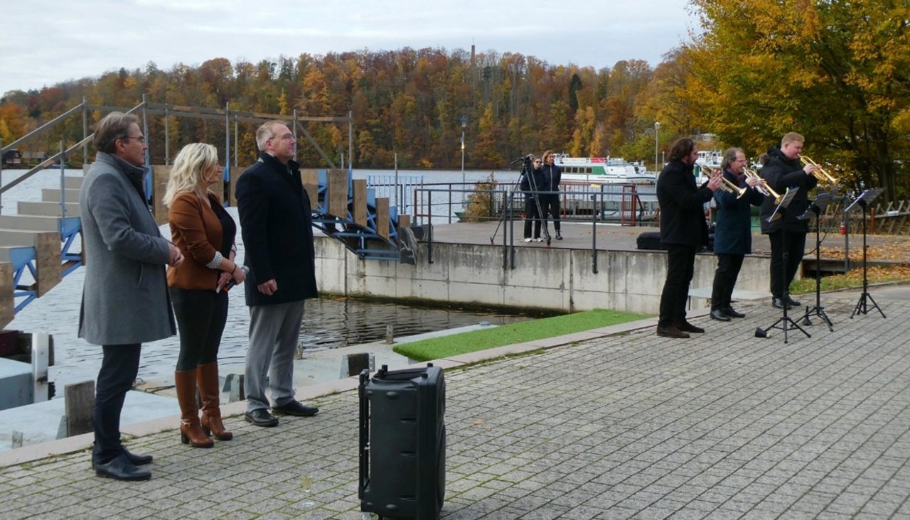 Quelle: Zweckverband Kriebsteintalsperre Man sieht drei Personen die eine Blaskapelle zuhören.