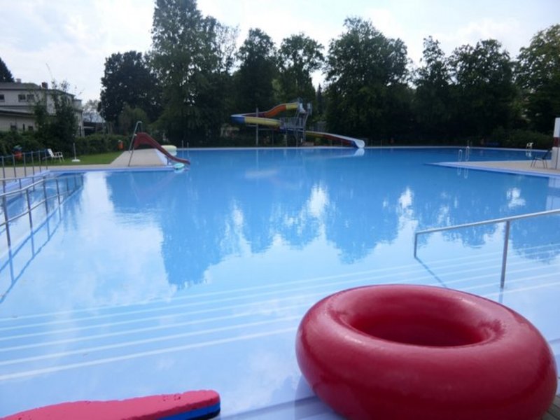Das Bild zeigt ein Außenschwimmbecken mit einem aufblasbaren Schwimmreifen am Rand.