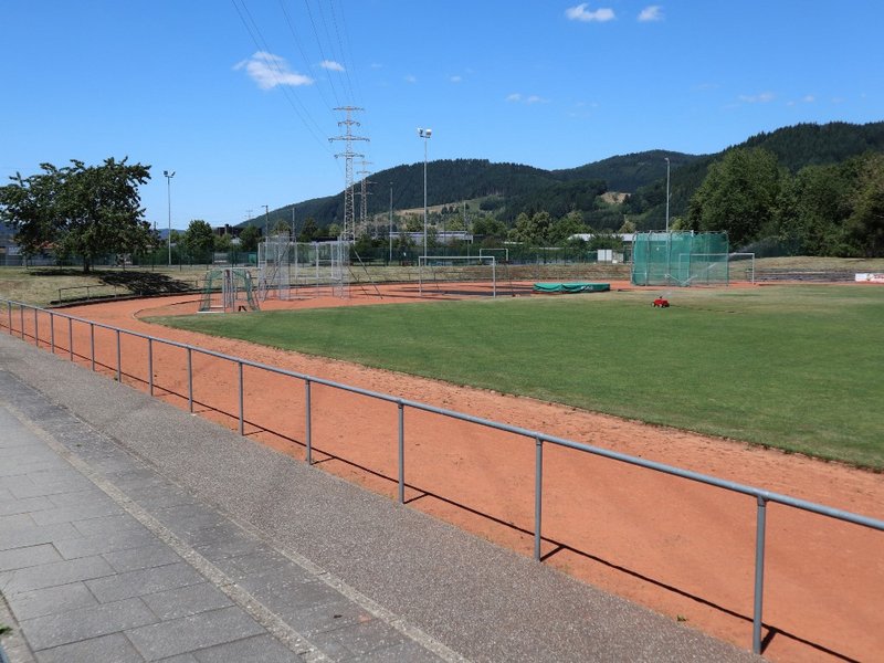 Man sieht eine Sportanlage mit Aschebahn und Rasen.