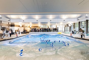 © Christina Czybik / bundesfoto Das Bild zeigt ein Wellenbadbecken mit Wasserbällen darin. Um das Becken herum stehen mehrere Menschen.