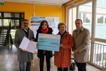 Das Bild zeigt eine Gruppe aus vier Menschen. Zwei von ihnen halten gemeinsam einen Förderscheck in Händen.