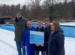 Quelle: Niklas Ernst Man sieht fünf Personen in einem verschneiten Freibad. die einen großen Spendenscheck halten.