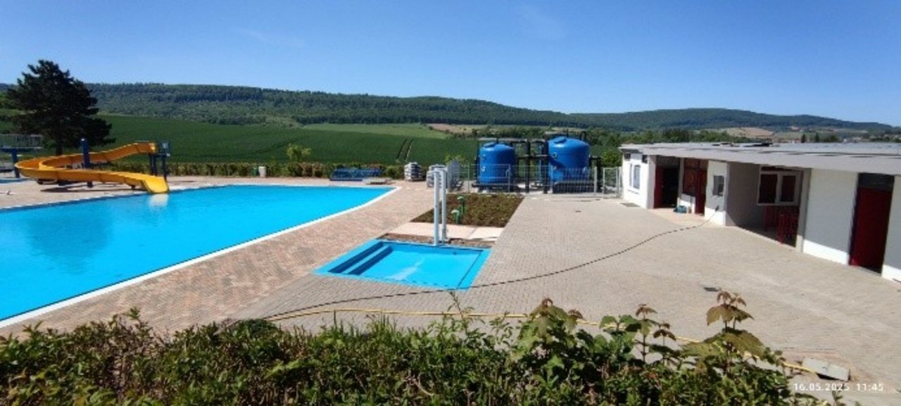 Das Bild zeigt ein Freibad mit einem großen Pool und einer Rutsche.
