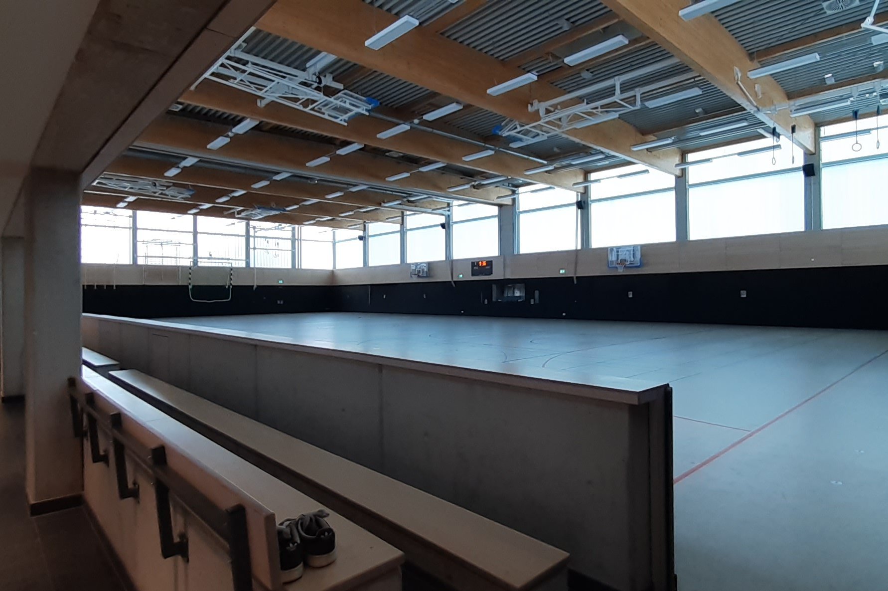 Stadt Winsen (Luhe) Das Bild zeigt die sanierte Sporthalle mit Holzbalkendecke, großen Fenstern und einer Tribüne mit Sitzplätzen