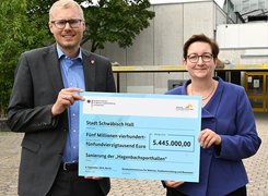 Franziska Kraufmann / Bundesfoto Das Bild zeigt eine Frau und einen Mann, die gemeinsam einen Förderscheck halten.