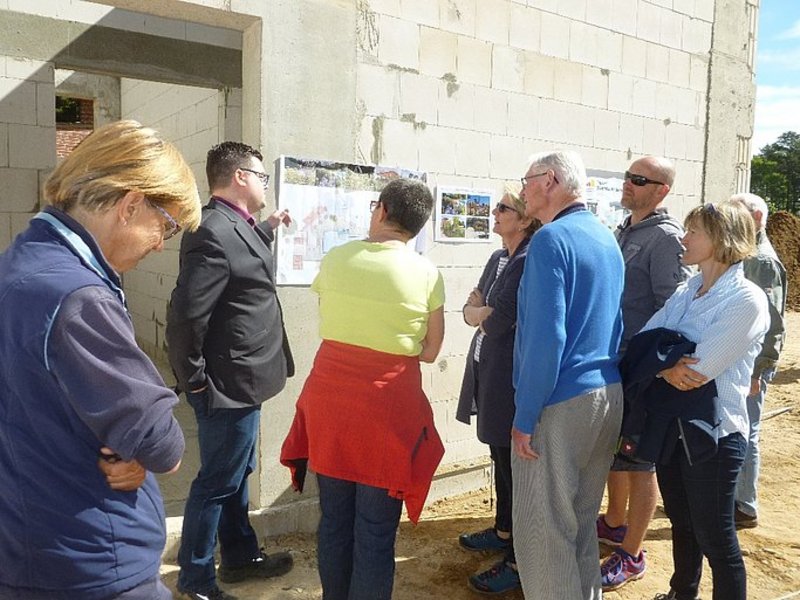 Das Bild zeigt mehrere Personen die einen Plan an einem Rohbaugebäude betrachten.