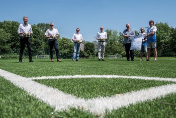 Das Bild zeigt mehrere Männer in einer Gruppe auf einem Fuballfeld.