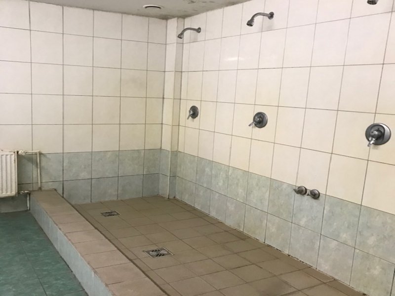 Man sieht eine Gemeinschaftsdusche mit drei Duschköpfen.
