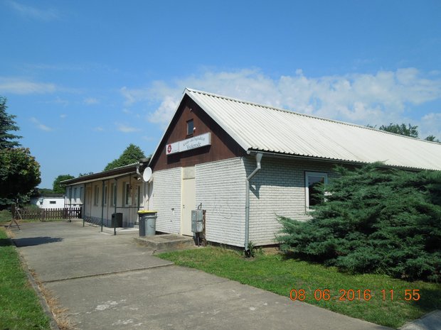 Einfahrt zu einem Vereingebäude mit Wellblechdach