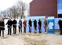 © Sascha Rühl / LK Cloppenburg Das Bild zeigt 10 Personen, die in einer Reihe stehen und jeweils einen Spaten in der Hand halten. Sie befinden sich auf einer Baustelle und symbolisieren den Baubeginn.