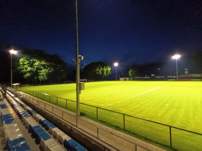 Das Bild zeigt ein Fußballfeld im Flutlichtschein.
