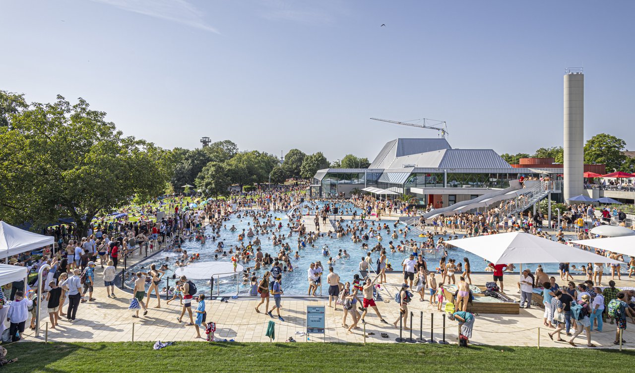Das Bild zeigt ein Freibad, wo viele Menschen baden.