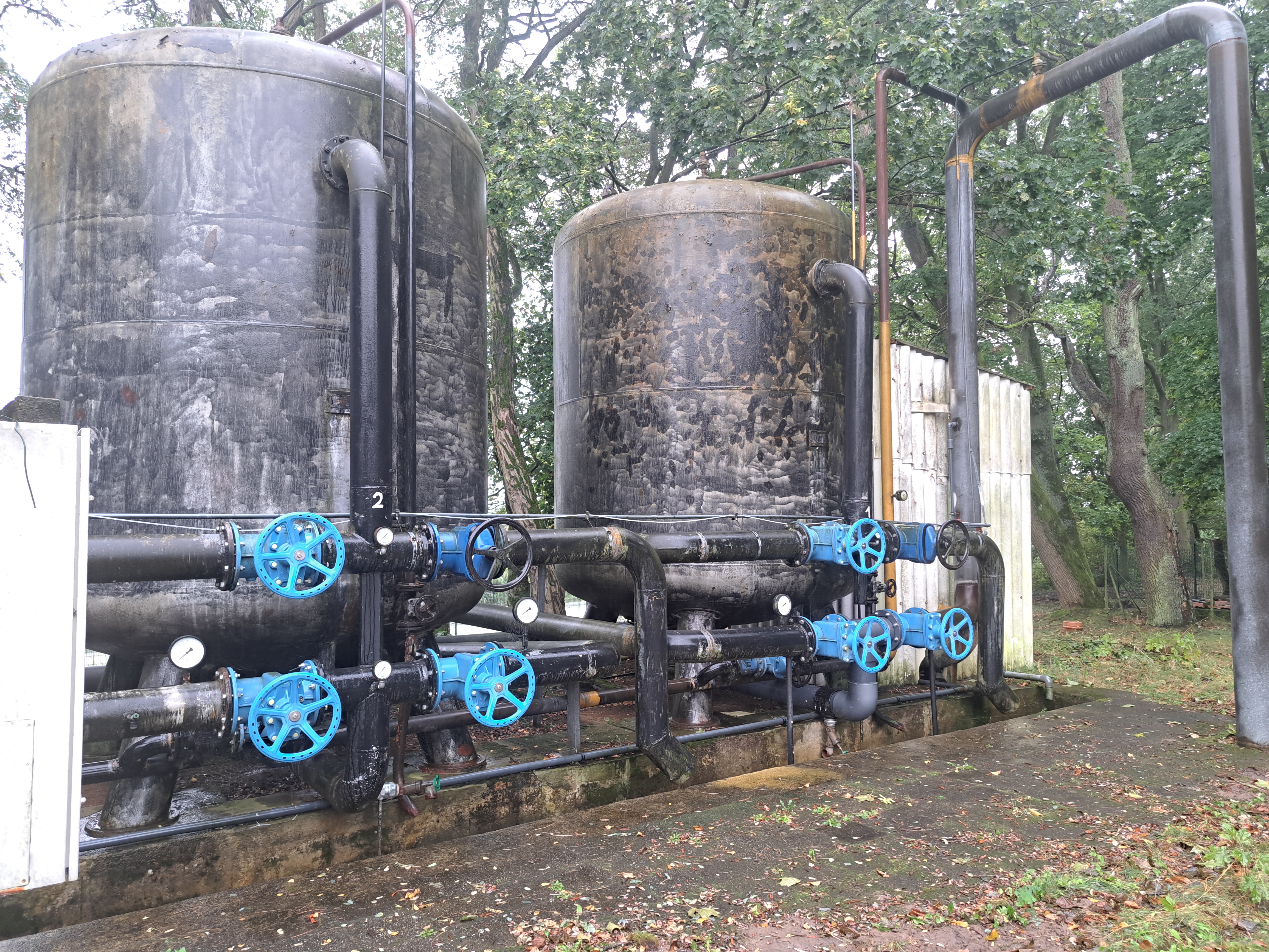 Man sieht eine alten Filteranlage in Form von zwei schwarzen Tanks.