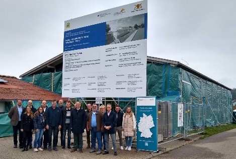 Das Bild zeigt 15 Personen vor einer Baustelle