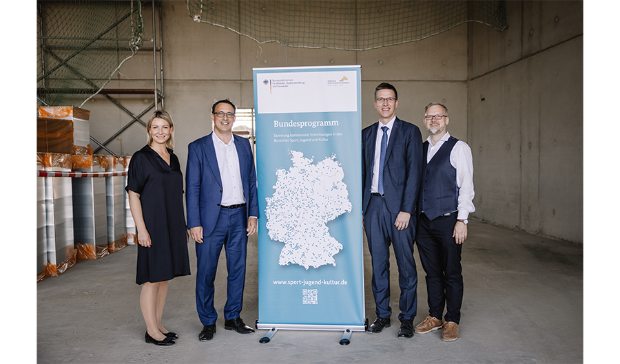 Das Bild zeigt 4 Personen die in einem Rohbau um den SJK Rollup stehen