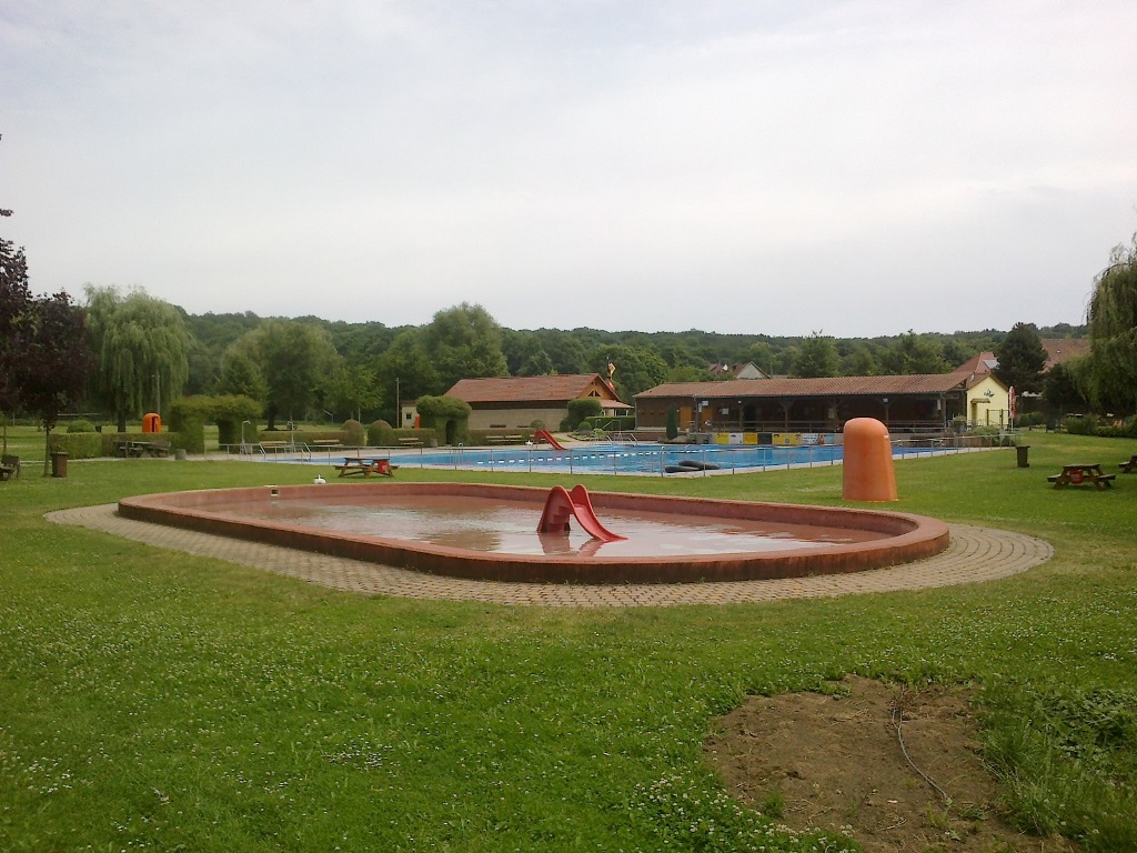 Das Bild zeigt das Sommerbad mit Kinderschwimmbecken, Schwimmerbecken und Gebäude.