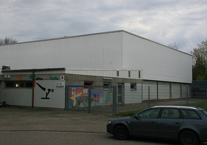 Das Bild zeigt ein Flachdachgebäude mit weißer Verkleidung und bunten Bemalungen.