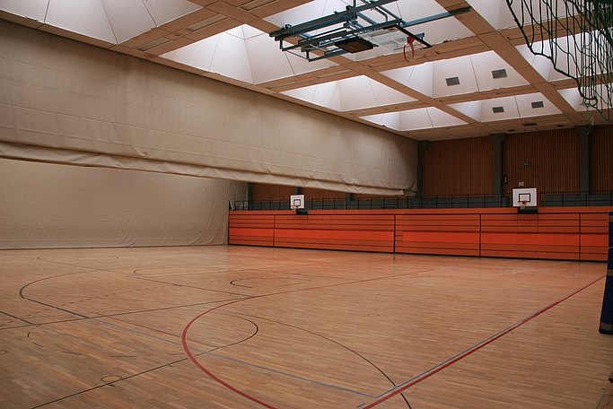 Das Bild zeigt eine Sporthalle mit Trennwänden und Holzverkleidung an den Wänden.
