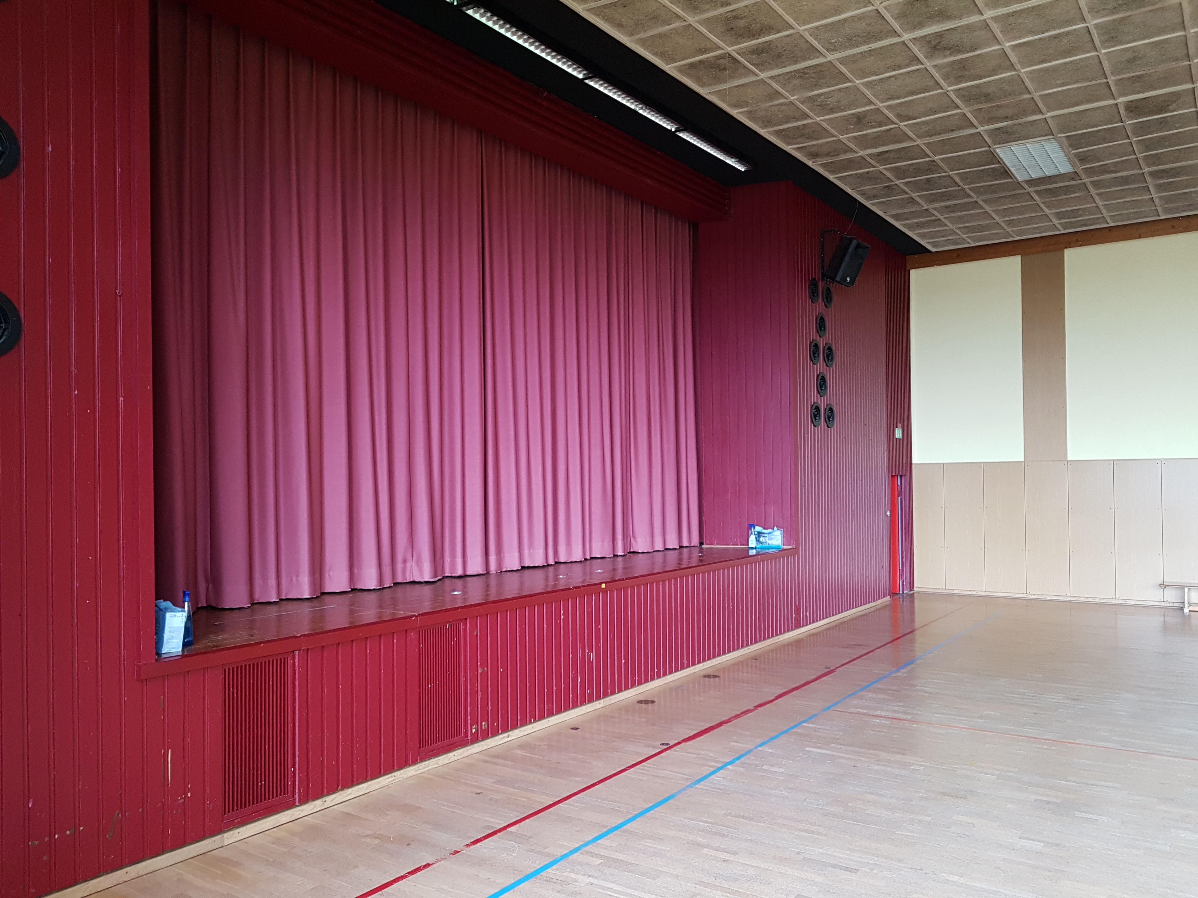Das Bild zeigt eine Bühne mit geschlossenem Theatervorhang.