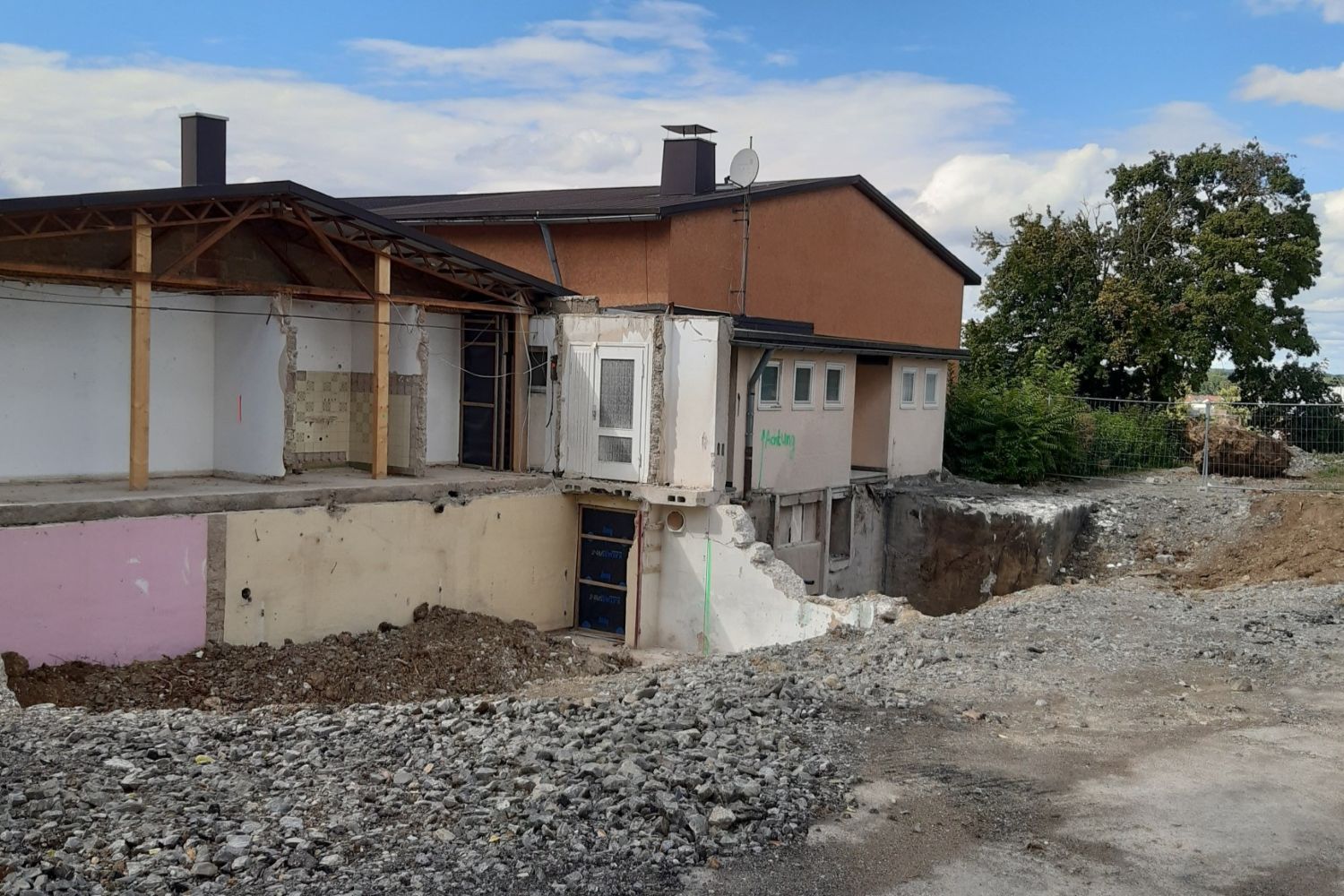 Stadt Bad Friedrichshall Dsa Bilt zeigt ein teilweise abgerissenes Gebäude mit orangener Fassade und weißem Anbau, umgeben von Schutt und Erdarbeiten