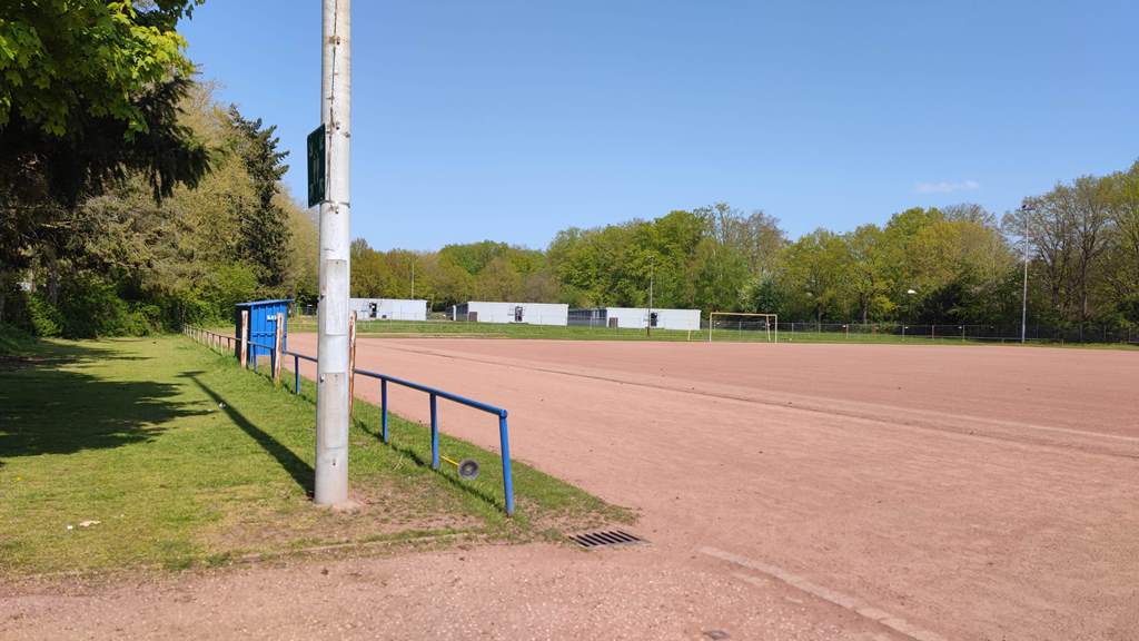 Das Bild zeigt einen Tennenplatz mit Rundlaufbahn vor dem Baubeginn.
