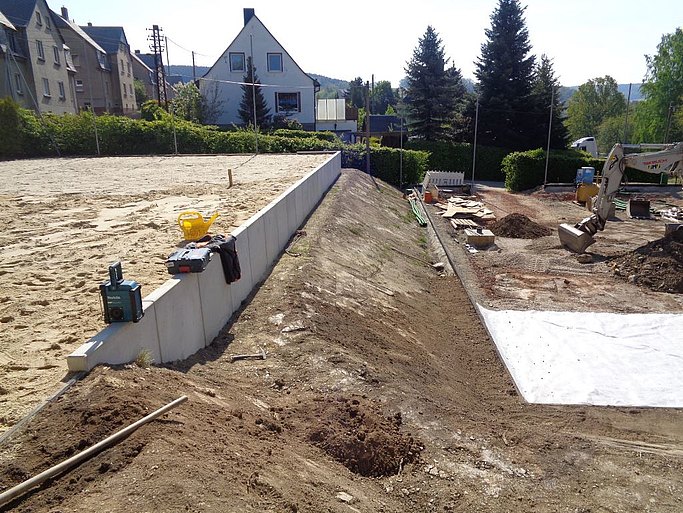 Das Bild zeigt die Bauarbeiten. Das Feld ist bereits mit Sand befüllt und ein Betonrand eingefügt.
