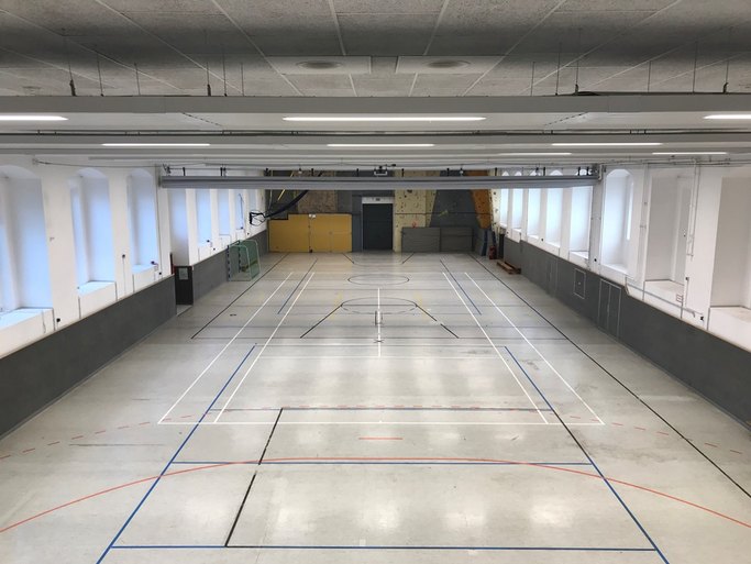 Das Bild zeigte eine Sporthalle mit verschiedenen Markierungen, einem Handballtor und einer Boulderwand.
